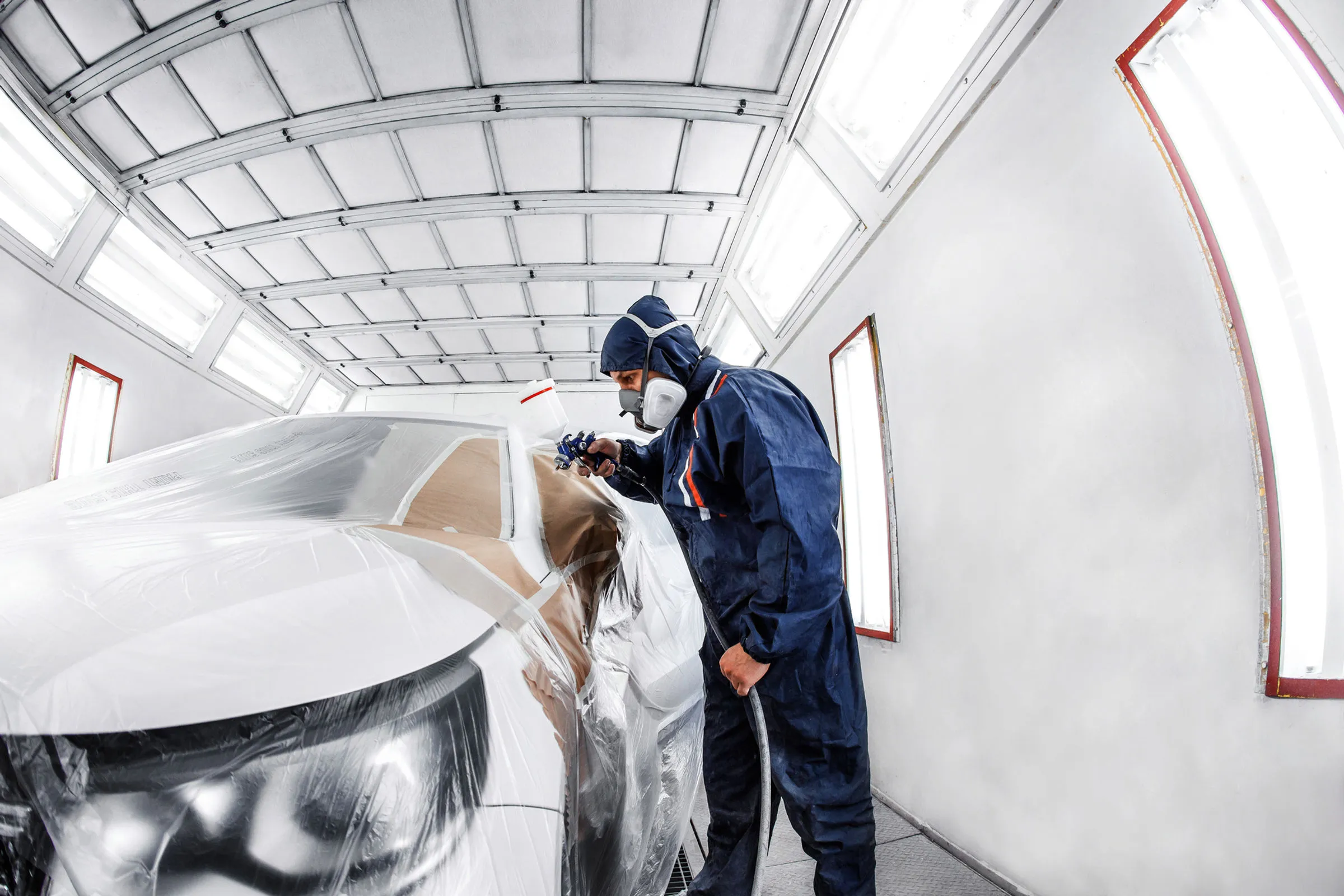 Technician refinishing a car in the paint booth at Spanky's Collision Repair